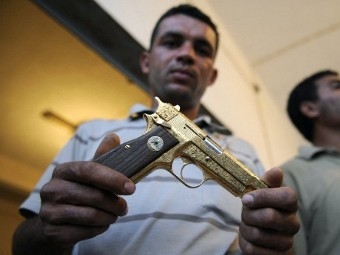 Боец НПС демонстрирует принадлежавший Каддафи золотой пистолет. Фото ©AFP